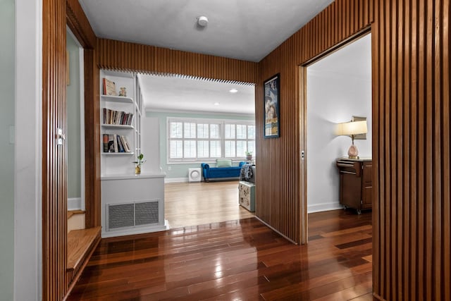 hall with dark wood-style floors, visible vents, and baseboards