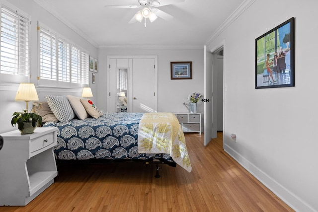 bedroom featuring baseboards, ceiling fan, ornamental molding, light wood-style floors, and a closet