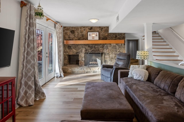 living room featuring a fireplace, wood finished floors, visible vents, french doors, and stairway