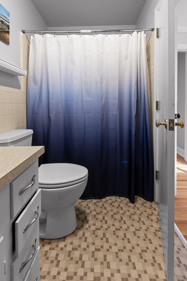 full bath featuring toilet, a shower with curtain, tile walls, and vanity