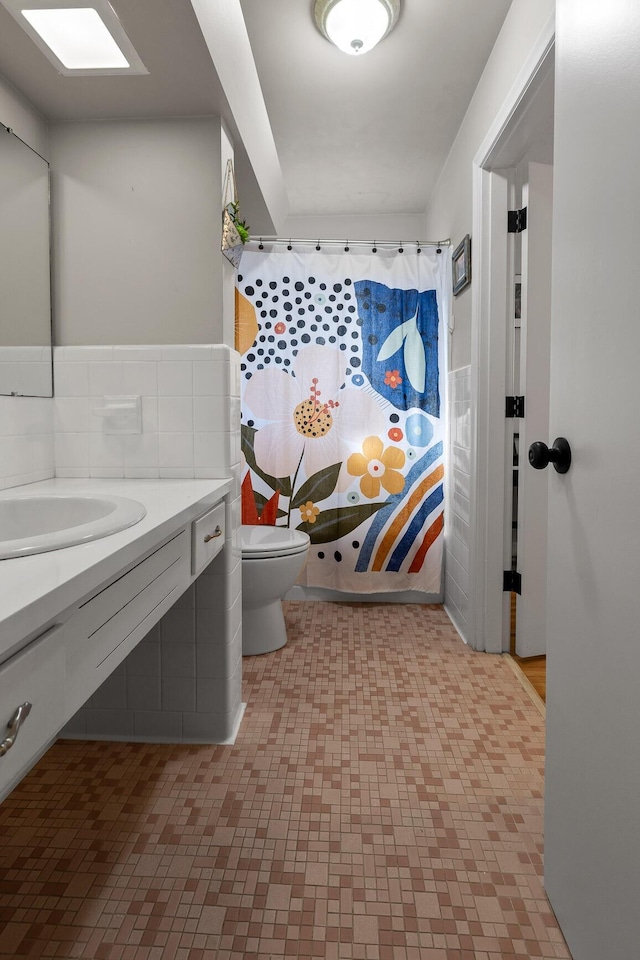 full bathroom featuring a skylight, a sink, backsplash, and toilet