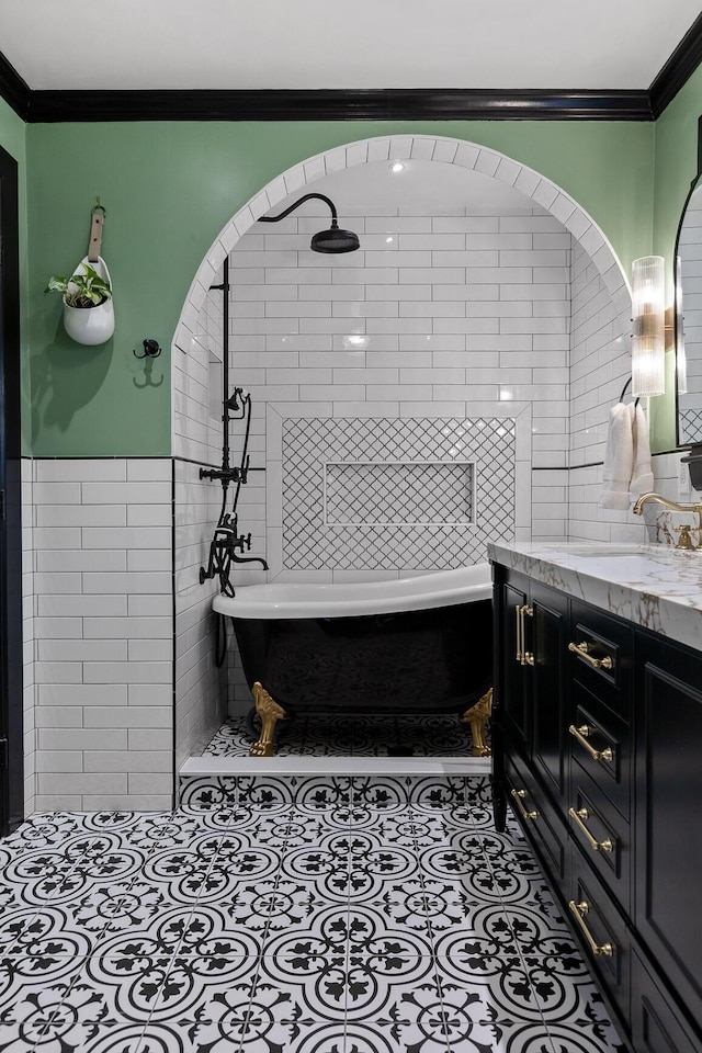 full bath with ornamental molding, tile patterned floors, a freestanding bath, vanity, and tile walls