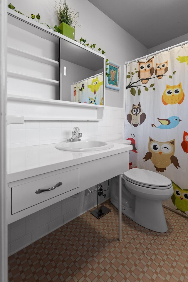 full bath featuring a sink, toilet, and tile walls