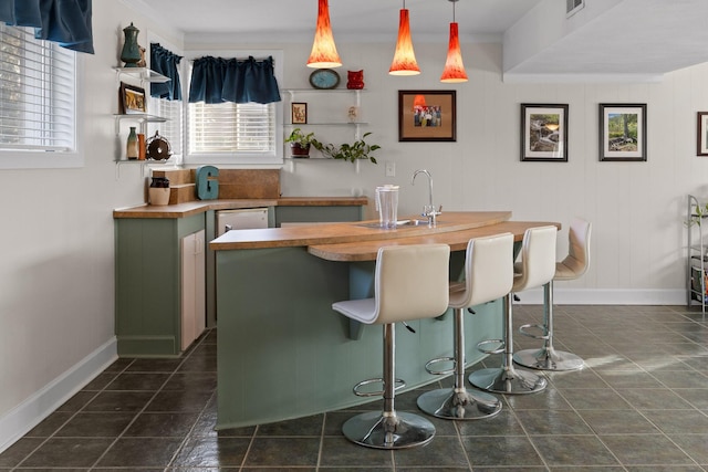 bar featuring hanging light fixtures, dark tile patterned floors, baseboards, and a sink