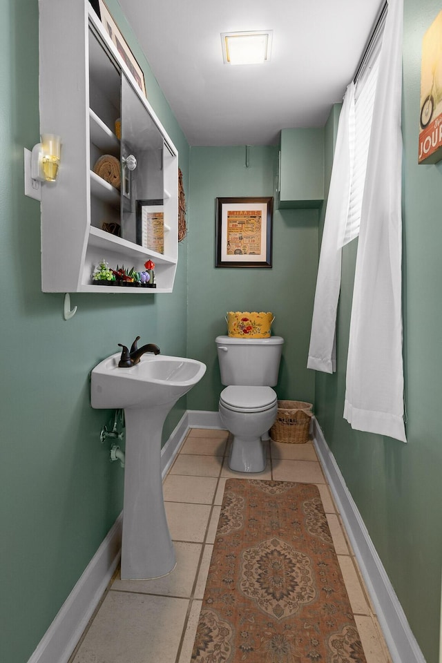 half bath featuring toilet, tile patterned flooring, and baseboards