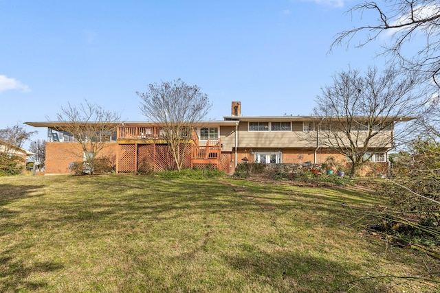 back of property featuring a deck, a yard, brick siding, and a chimney