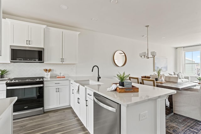 kitchen with white cabinets, decorative light fixtures, a peninsula, stainless steel appliances, and a sink