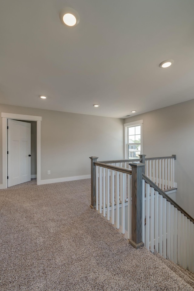 hallway with carpet flooring, an upstairs landing, and recessed lighting