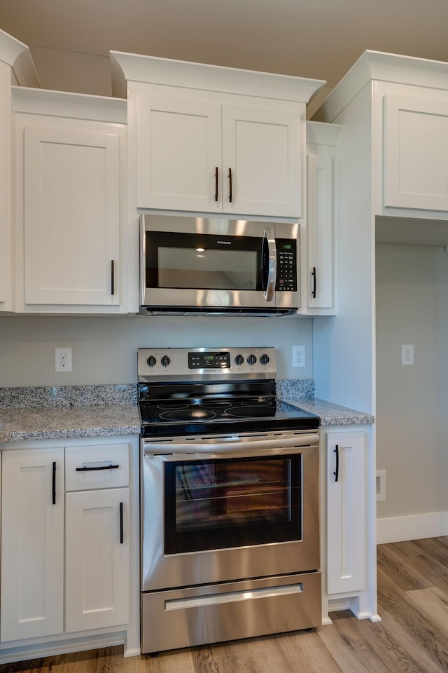 kitchen featuring appliances with stainless steel finishes, white cabinets, and light stone counters