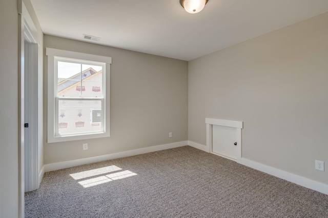 empty room featuring visible vents, light carpet, and baseboards