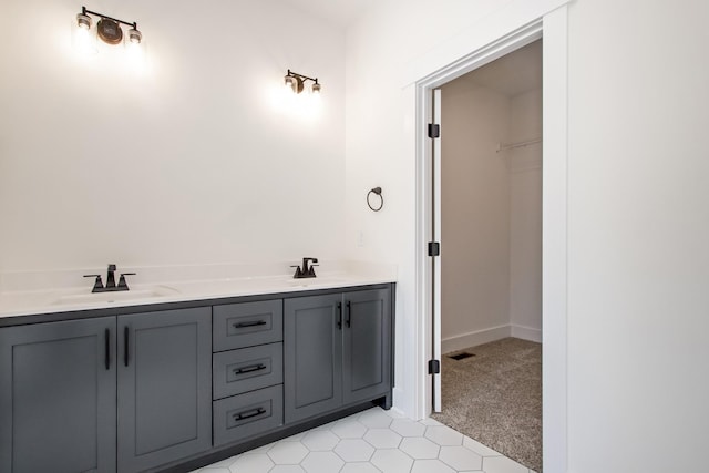 full bathroom featuring visible vents, double vanity, a sink, and a walk in closet