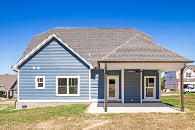 rear view of house with a shingled roof, a patio area, ceiling fan, and a lawn