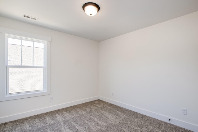 carpeted spare room with visible vents and baseboards