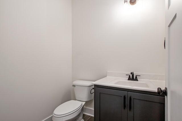 bathroom with baseboards, vanity, and toilet