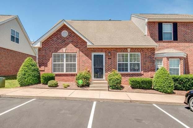 view of front of house featuring uncovered parking, brick siding, and a shingled roof