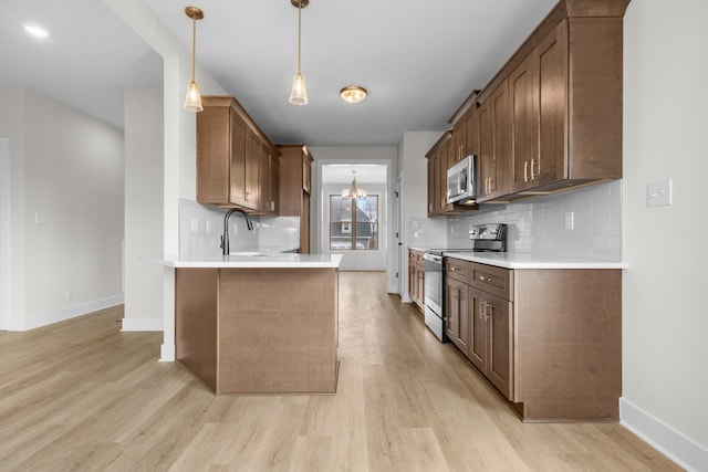 kitchen featuring appliances with stainless steel finishes, pendant lighting, light countertops, and a sink