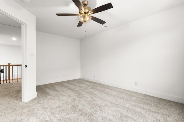 empty room with a ceiling fan, light colored carpet, visible vents, and baseboards