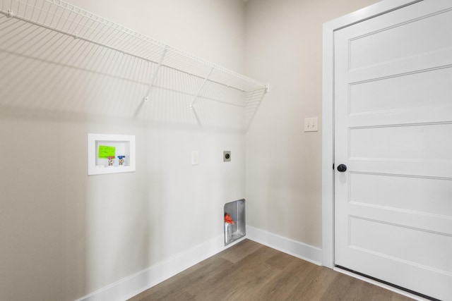 clothes washing area with dark wood-style floors, hookup for a washing machine, electric dryer hookup, laundry area, and baseboards