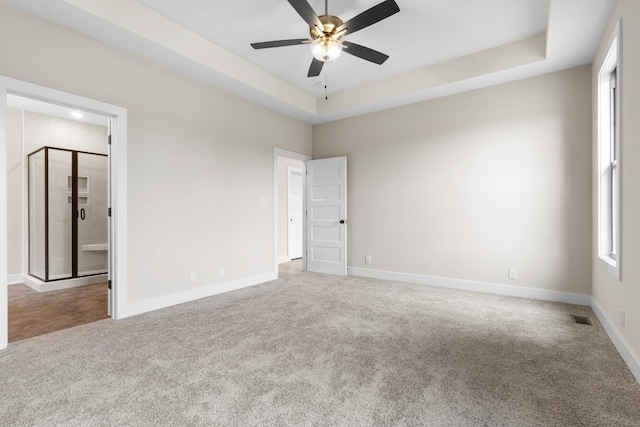 carpeted empty room with a raised ceiling, visible vents, ceiling fan, and baseboards