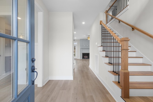 foyer featuring a fireplace, recessed lighting, stairway, light wood-style floors, and baseboards