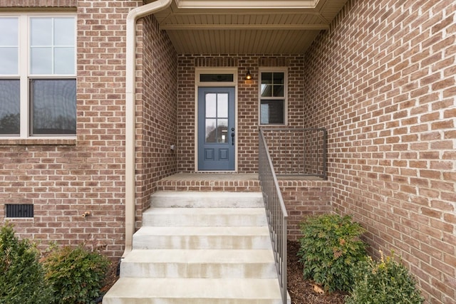 entrance to property featuring crawl space and brick siding