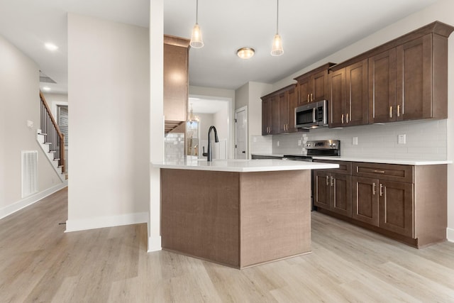 kitchen featuring stainless steel appliances, pendant lighting, light countertops, and decorative backsplash