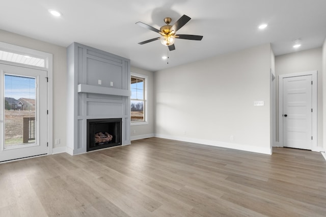 unfurnished living room featuring a large fireplace, light wood-style flooring, and baseboards