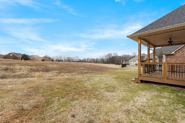 view of yard with a deck and ceiling fan