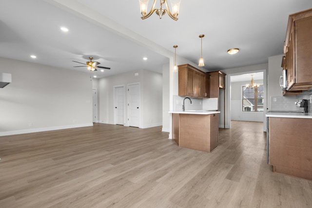 kitchen featuring light countertops, open floor plan, brown cabinets, and decorative light fixtures