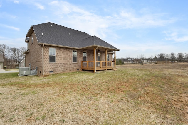 back of property with a shingled roof, central AC unit, crawl space, a yard, and brick siding