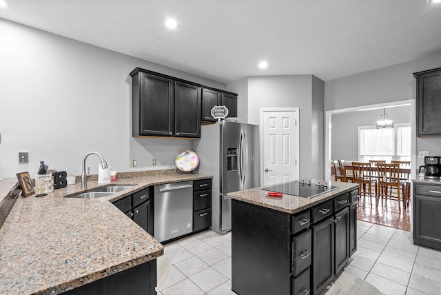 kitchen featuring light tile patterned floors, a center island, light stone countertops, stainless steel appliances, and a sink