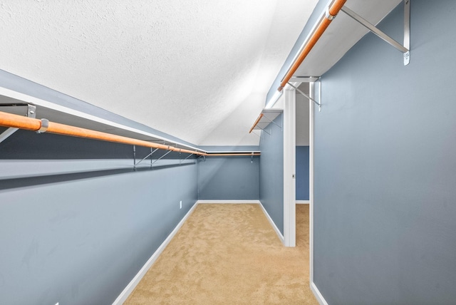 spacious closet with lofted ceiling and light colored carpet