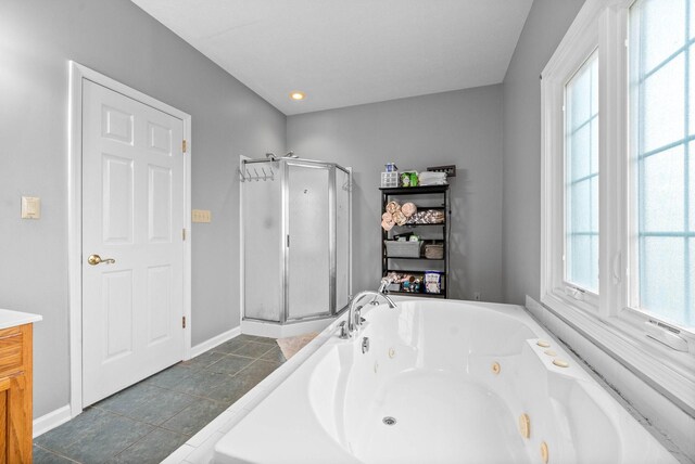 bathroom with a stall shower, baseboards, vanity, and a tub with jets