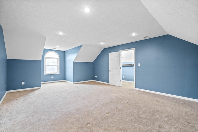 bonus room featuring light carpet, baseboards, and a textured ceiling