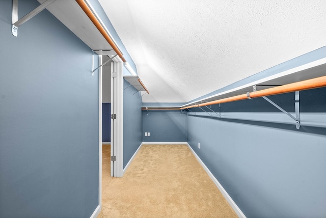 spacious closet with light carpet and vaulted ceiling