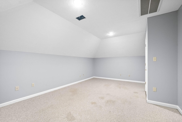 additional living space featuring carpet, visible vents, lofted ceiling, and baseboards