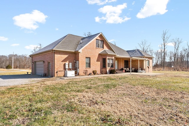 view of front of property featuring brick siding, a porch, a garage, driveway, and a front lawn