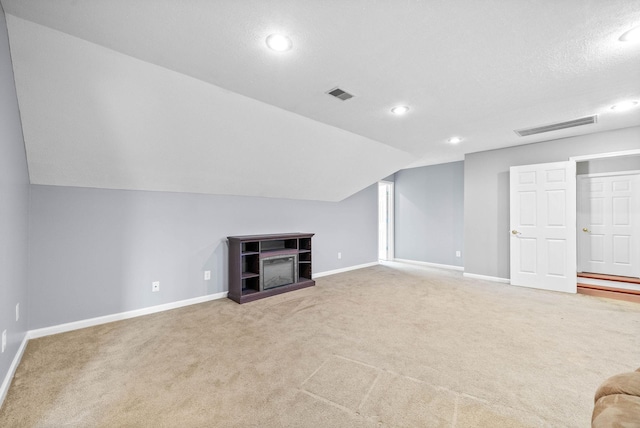 unfurnished living room with carpet, visible vents, lofted ceiling, and baseboards