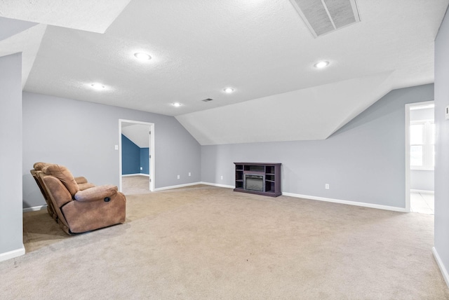 living area featuring a textured ceiling, light carpet, a fireplace, visible vents, and baseboards