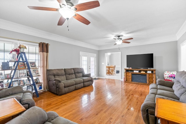 living room featuring a healthy amount of sunlight, ornamental molding, wood finished floors, and french doors