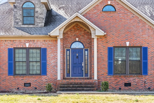 entrance to property with crawl space, roof with shingles, and brick siding