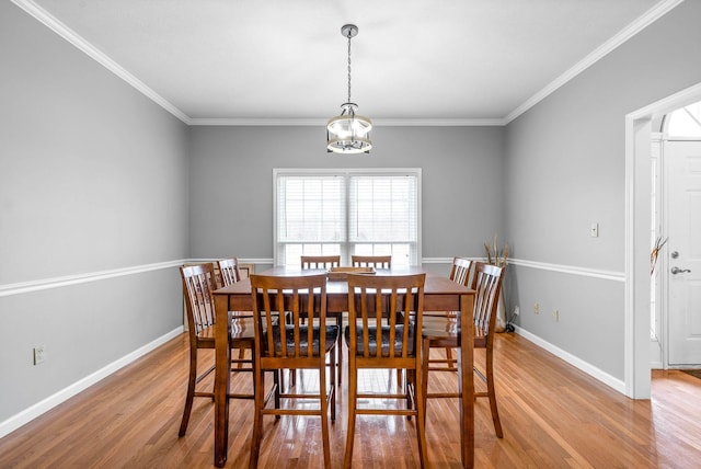 dining space with light wood-style floors, baseboards, crown molding, and an inviting chandelier