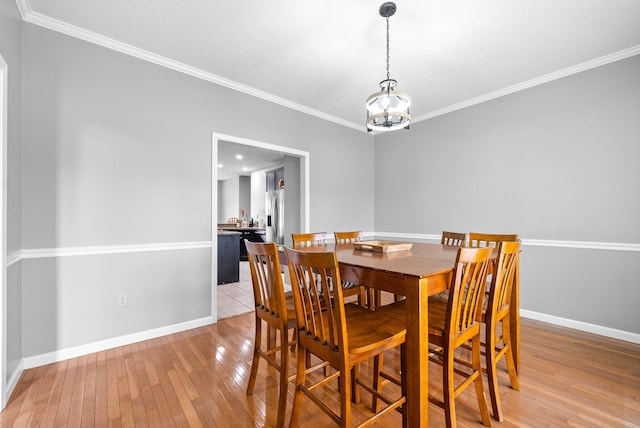 dining area featuring baseboards, ornamental molding, an inviting chandelier, and light wood-style floors