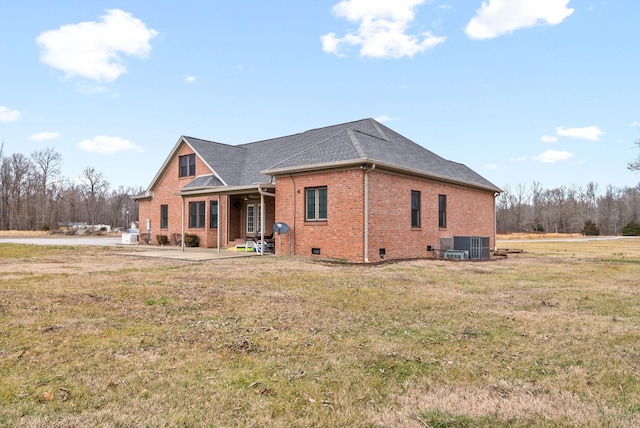 exterior space with a patio, central air condition unit, brick siding, a yard, and crawl space