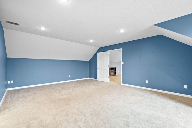 bonus room with a textured ceiling, light carpet, visible vents, and baseboards