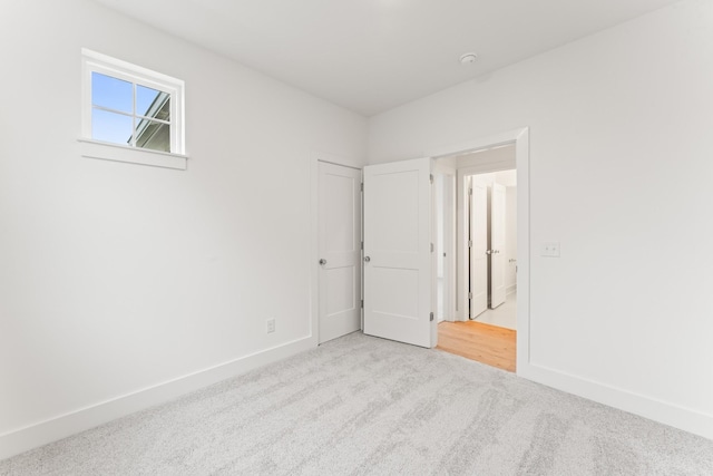 unfurnished bedroom featuring light carpet and baseboards