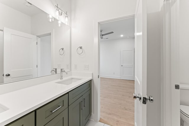 full bath with baseboards, vanity, toilet, and wood finished floors