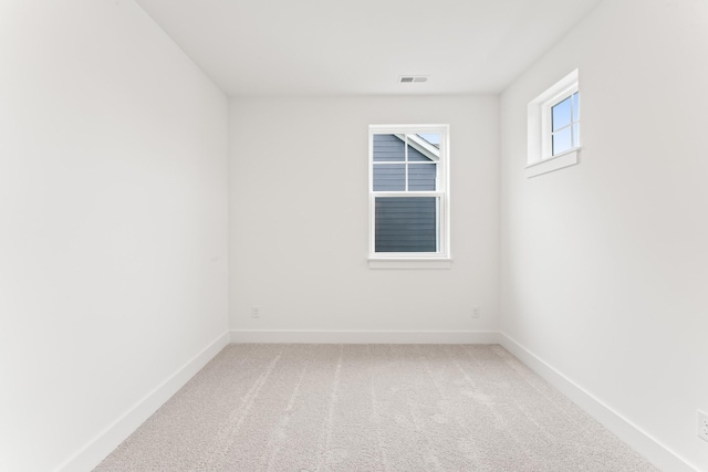 carpeted spare room featuring visible vents and baseboards