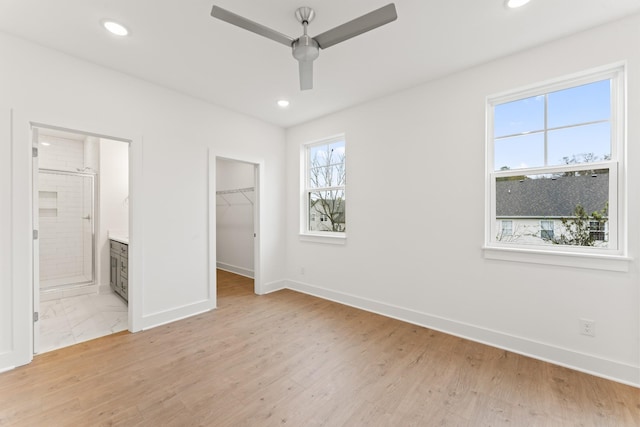 unfurnished bedroom featuring baseboards, light wood-type flooring, a walk in closet, and recessed lighting