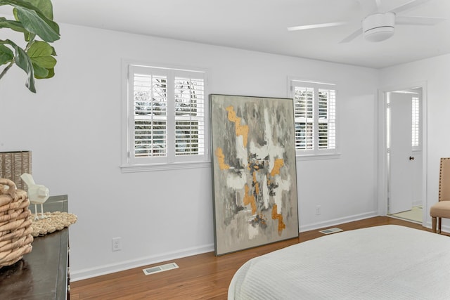 bedroom featuring a ceiling fan, baseboards, visible vents, and wood finished floors